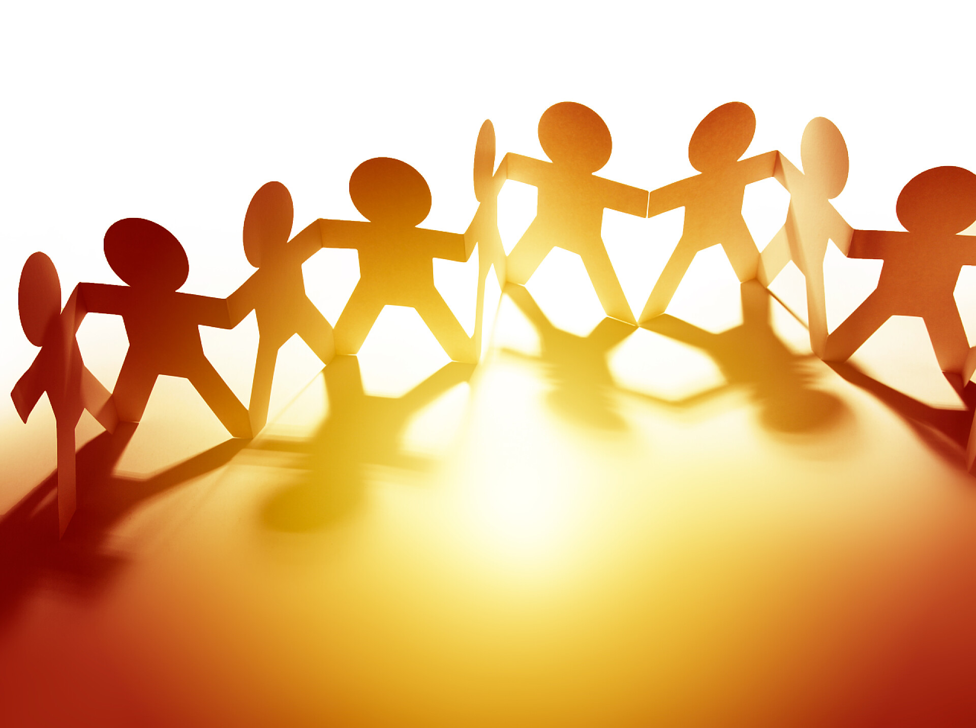 在阳光普照下的几个剪纸小人一队纸链的人在一排牵手。复制空间