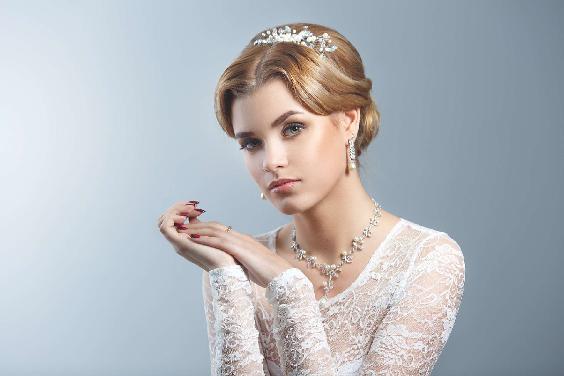 灰色的背景墙前一个美丽的新娘在看着镜头优雅的新娘的肖像与化妆和发型