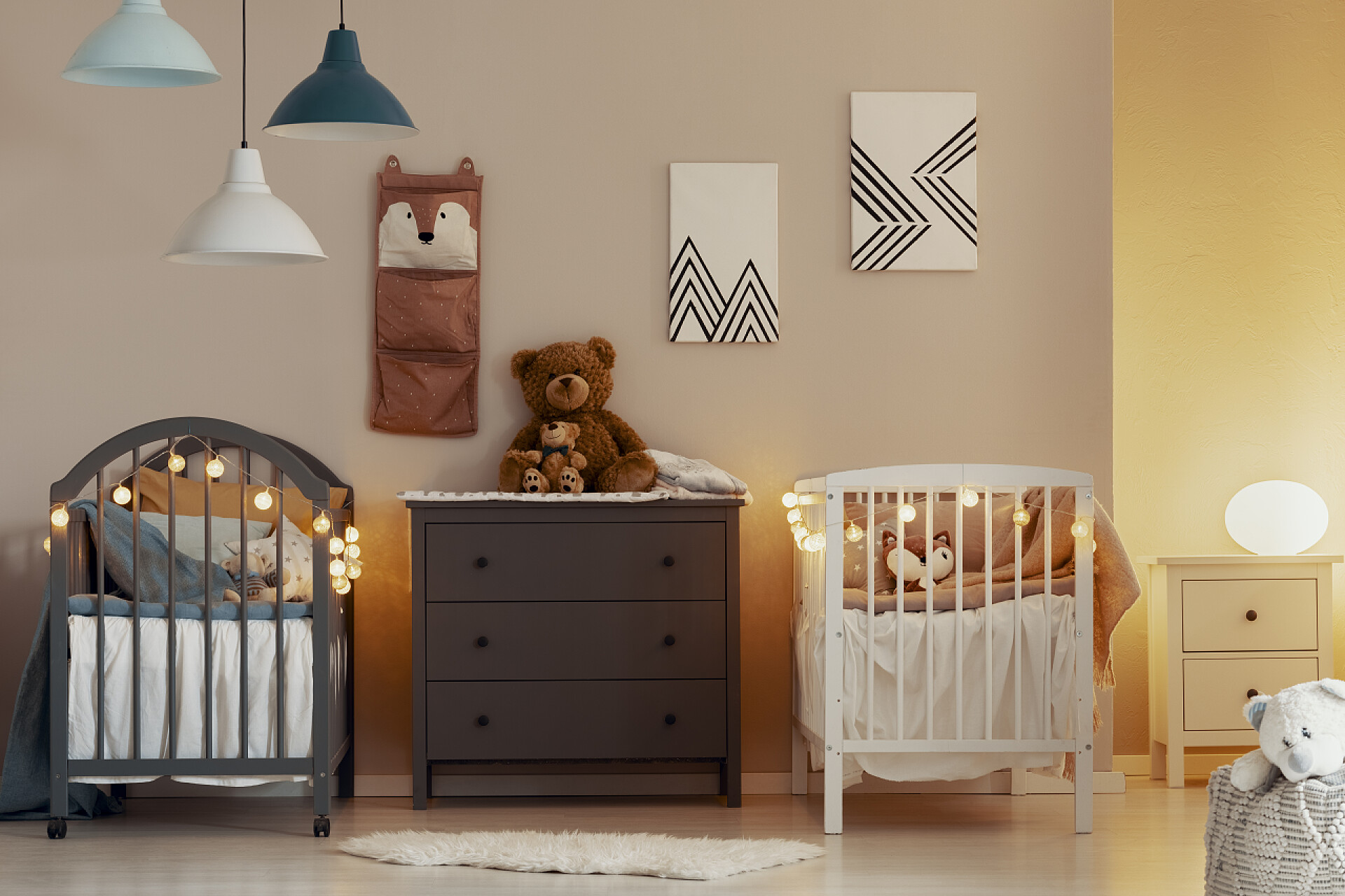 温馨的婴儿房温暖的婴儿卧室内部, 白色和灰色婴儿床, 梳妆台和小床头柜与灯