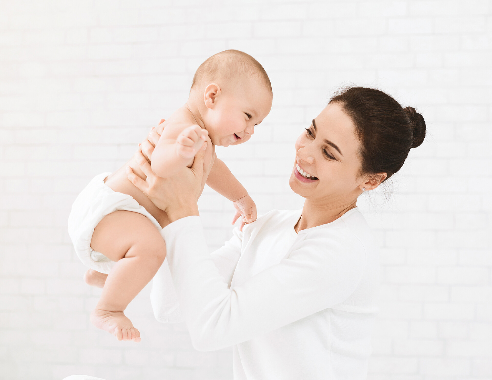 妈妈抱着宝宝在白色的背景下玩耍母亲为她可爱的宝宝做强化练习