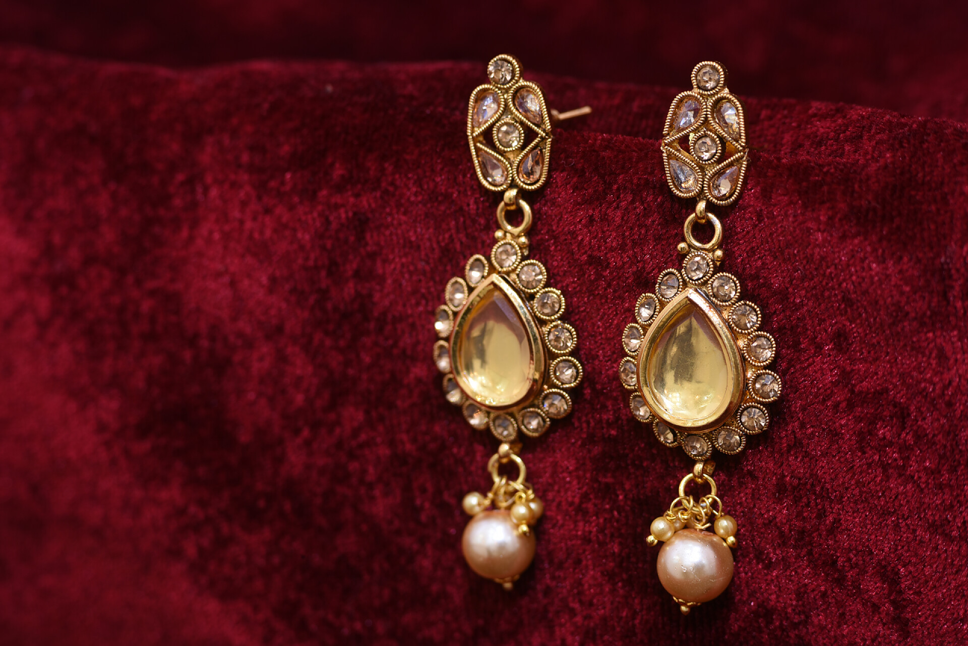 红色布料上的一对小坠对花哨的金色设计师耳环特写宏观图像在红色背景