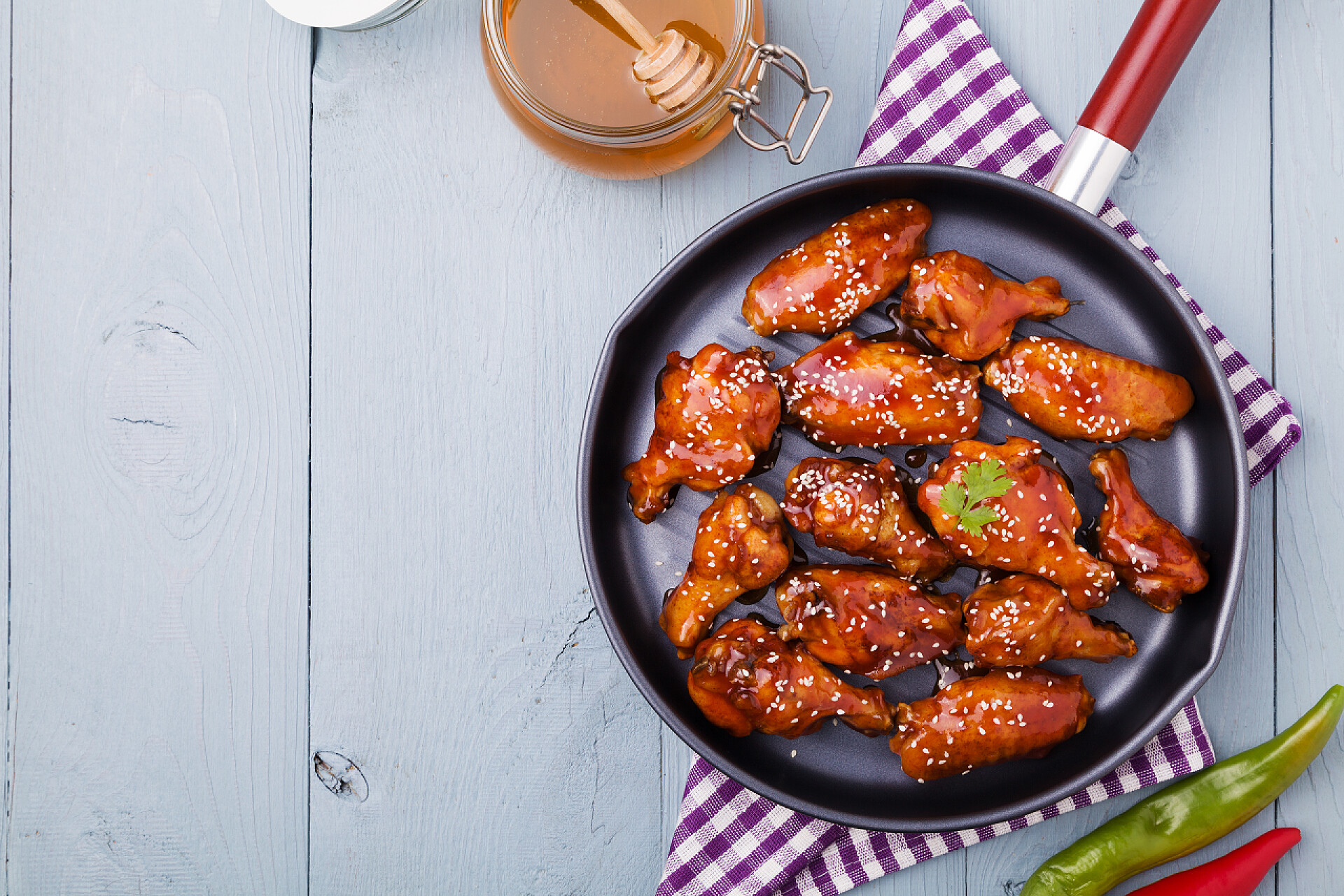 一个平底锅里的美味烤鸡翅用蜂蜜酱烤鸡翅, 洒上芝麻.