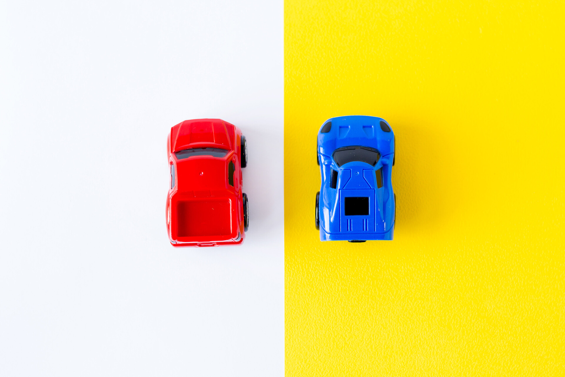 两个颜色不同的小汽车黄色背景视图上的微型玩具车. 汽车和运输概念