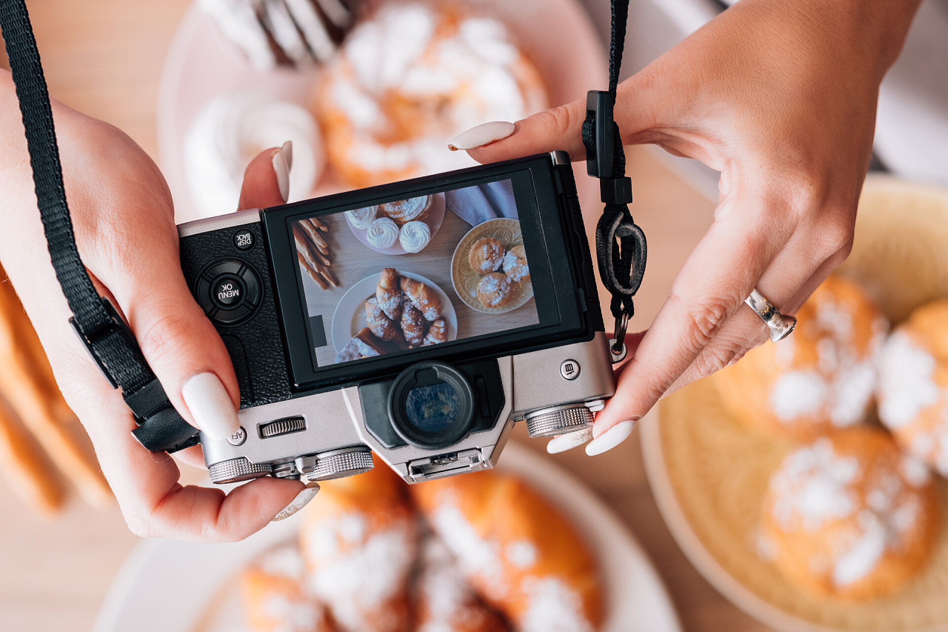 一个女人拿着相机在拍桌子上丰富的甜品烹饪博客蛋糕糕点甜面包店产品