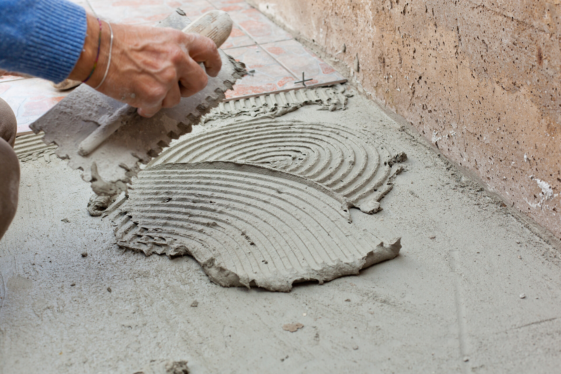 在地上涂抹水泥的男子砖瓦作品与地板.