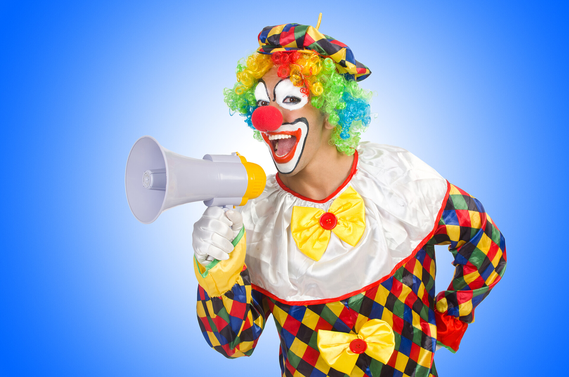 搞怪的小丑拿着喇叭小丑与扬声器上白