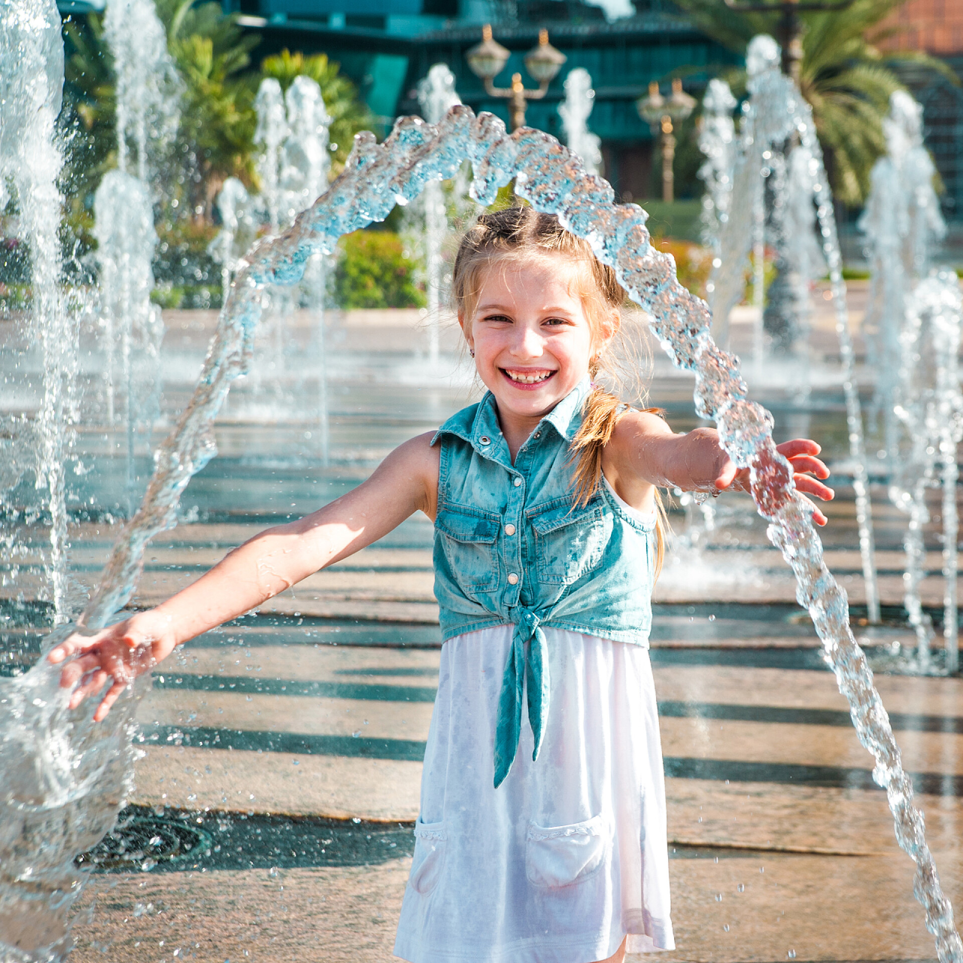 漂亮的小女孩在玩水在喷泉开心的小女孩