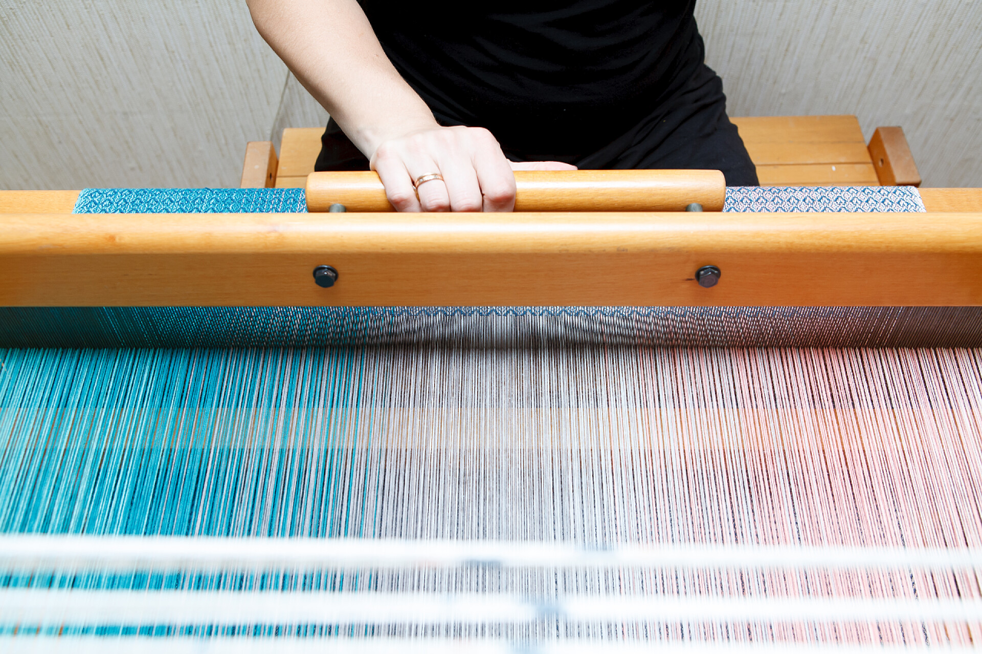 女人用纺织机在织布在织布机上织一个女人的手