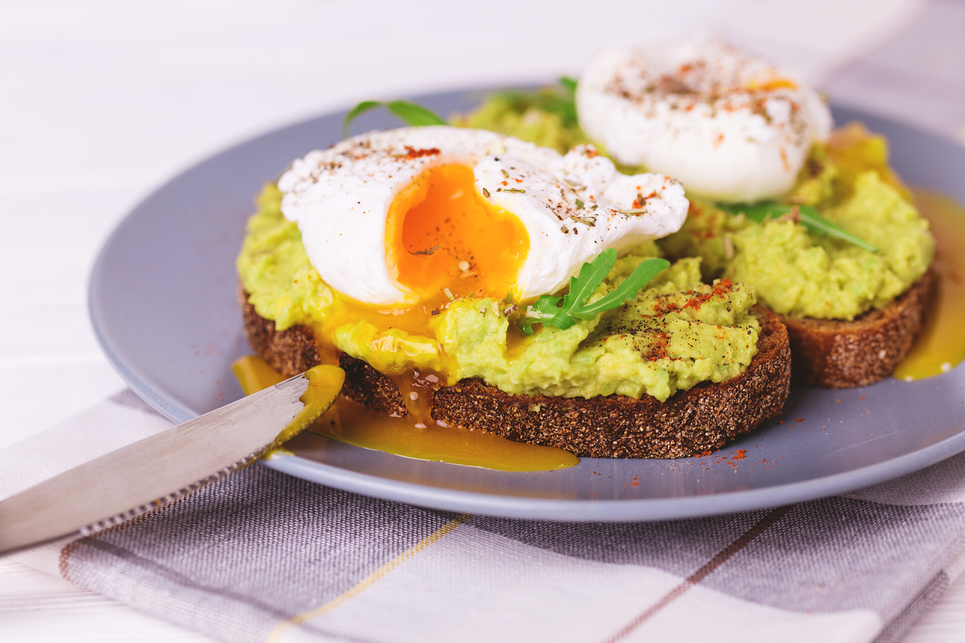 盘子里有烤面包和荷包蛋等美食烤面包，水煮鸡蛋、 牛油果、 香料和芝麻菜泥