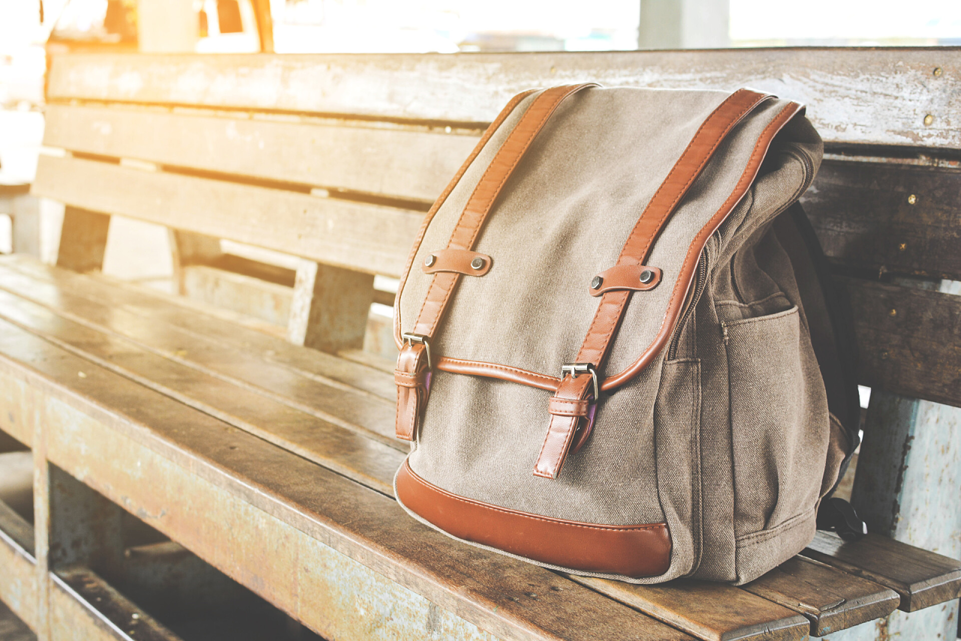 公共汽车总站木椅子上的棕色背包棕色纸袋在公共汽车总站的木椅子上