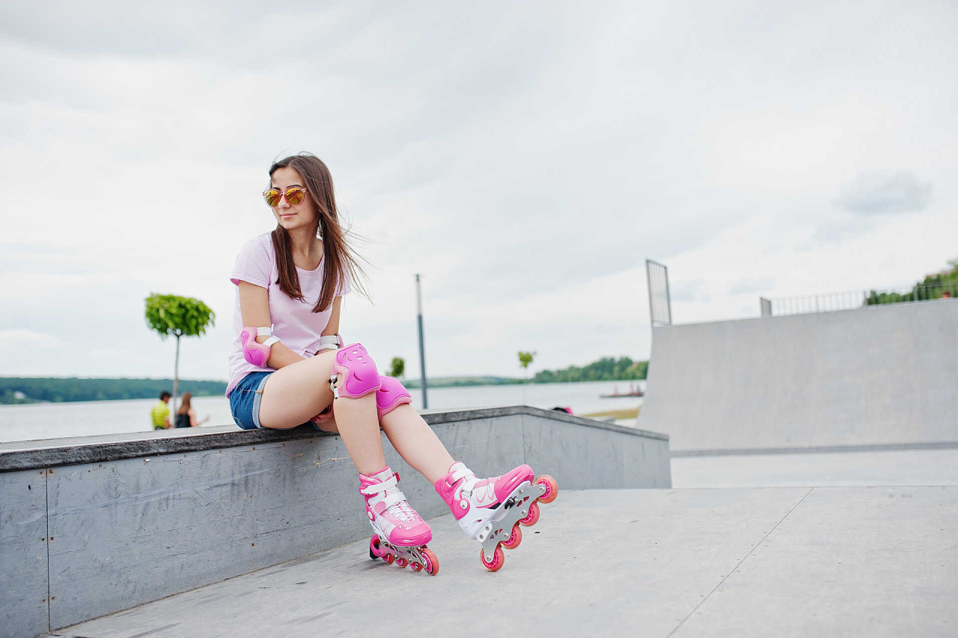 女孩在户外练习轮滑短裤，t 恤，sungla 迷人的年轻女人的画像