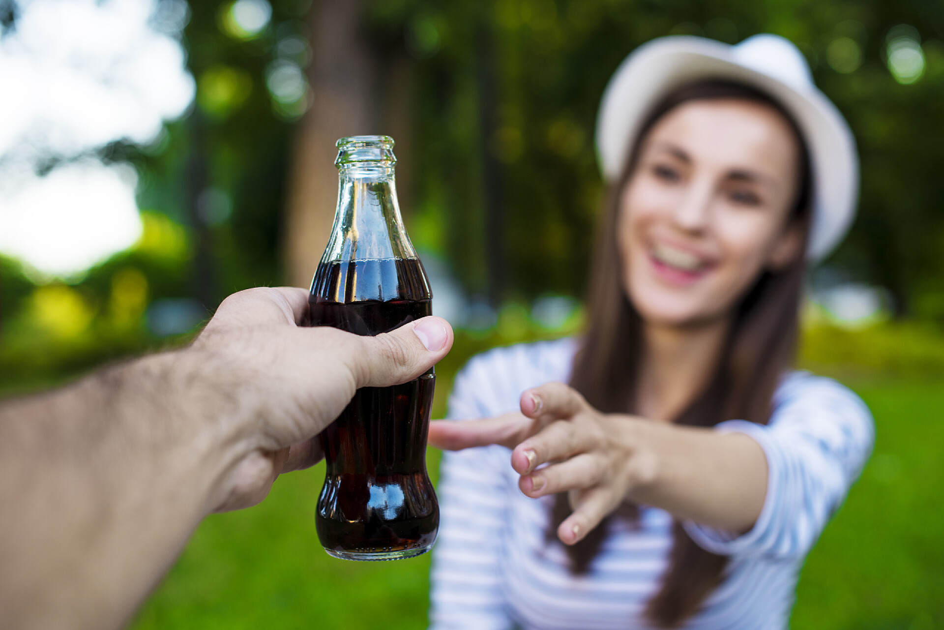 年轻女子在公园从男人手中拿一瓶冷饮女人拿一瓶冷饮