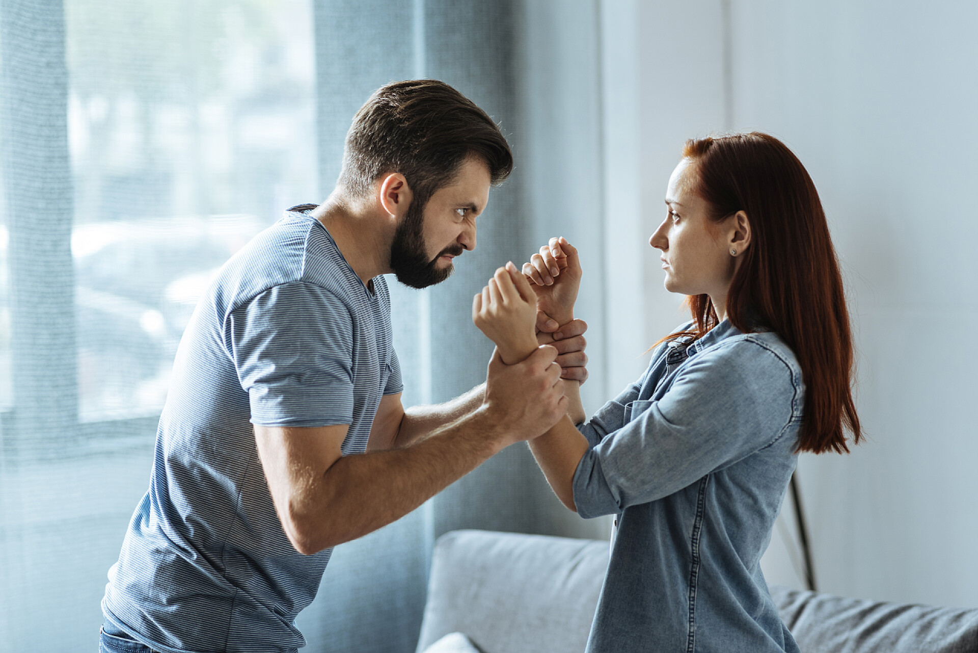 室内正在争吵对峙的一对夫妻愤怒强壮的男人，对自己的情绪失去控制