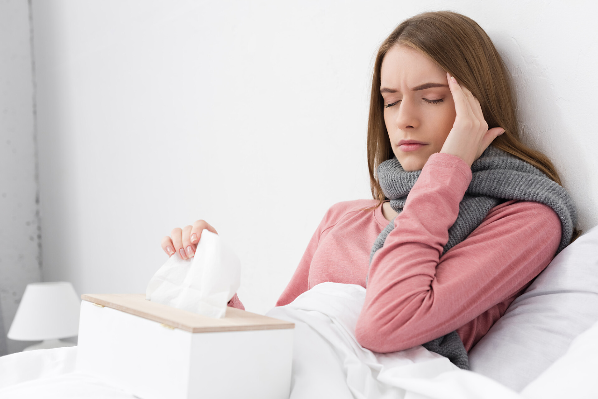 一个女人躺在床上扶着额头生病的女孩感到头痛 