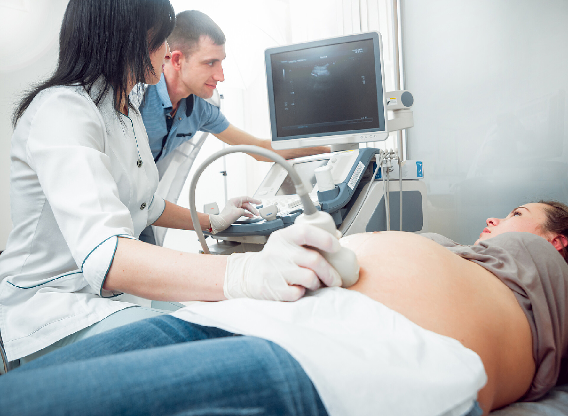 女医生正在给孕妇做超声波女医生和年轻孕妇与丈夫的病人。超声波设备。诊断.超声.