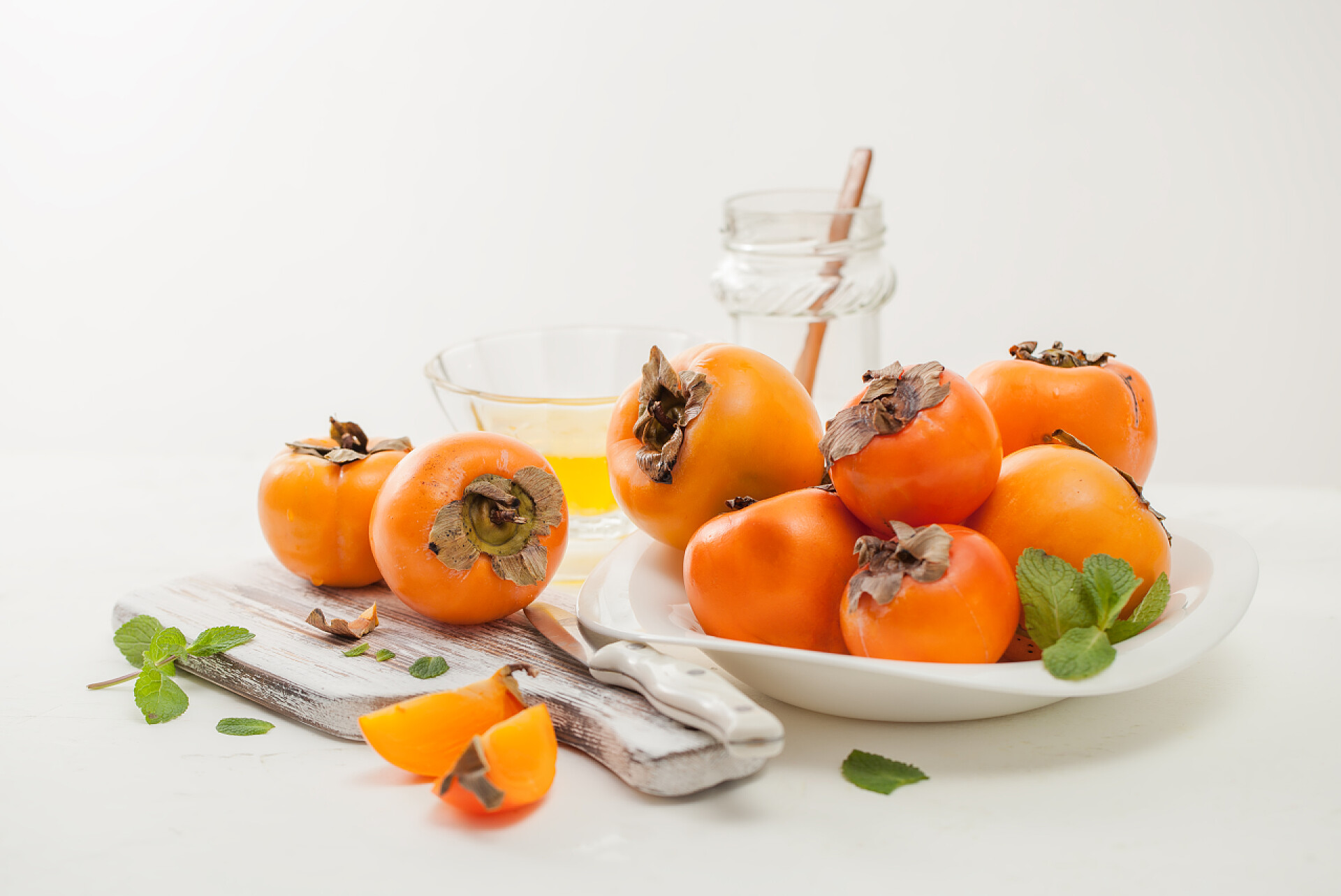 桌子上的一盘柿子一堆成熟的柿子在一张白色桌子上的碗里