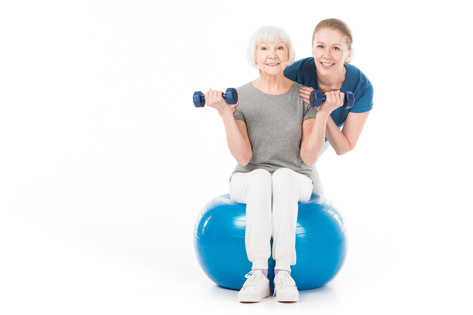 白色背景上做瑜伽的老人教练和运动员的画像与哑铃和健身球隔离在白色