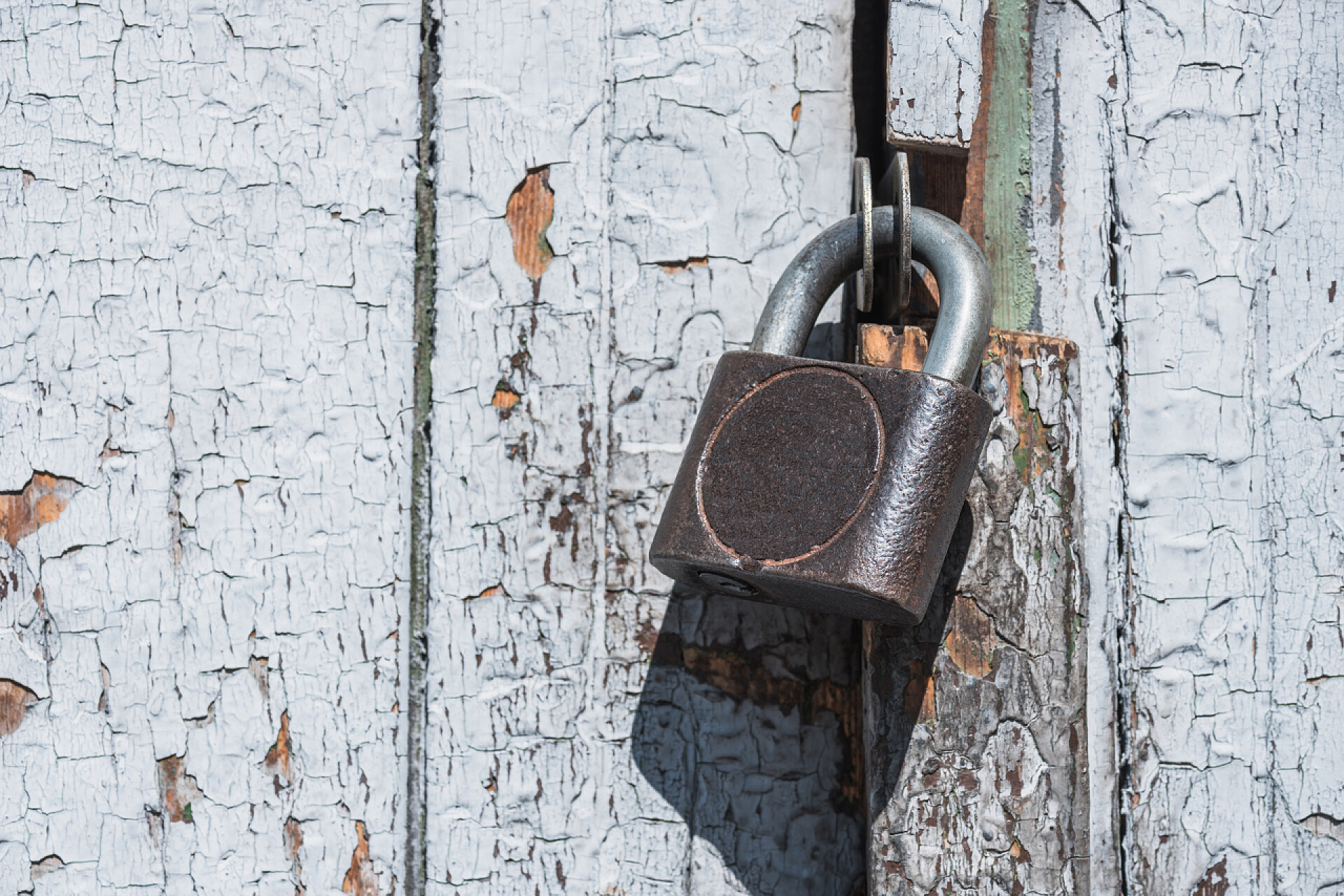 风化的旧木门上有把老式锁老式锁和风化刮漆旧木门特写视图