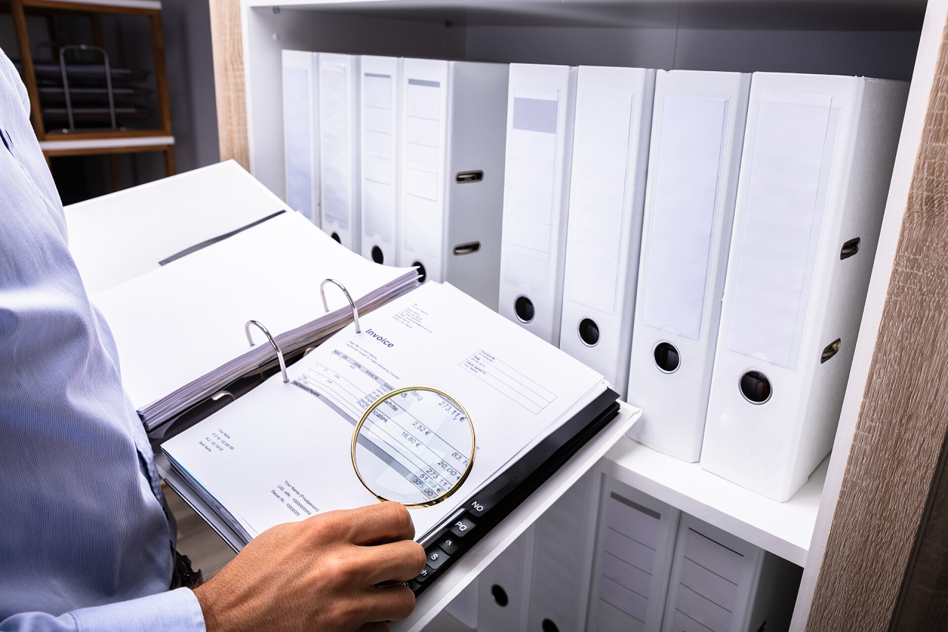 商人正拿着放大镜观看账单商人通过放大镜检查文件夹中的账单