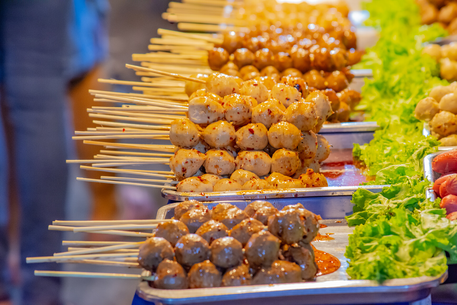 烧烤摊上的烤串烤猪肉肉丸和肉丸在托盘上与水辛辣的猫.