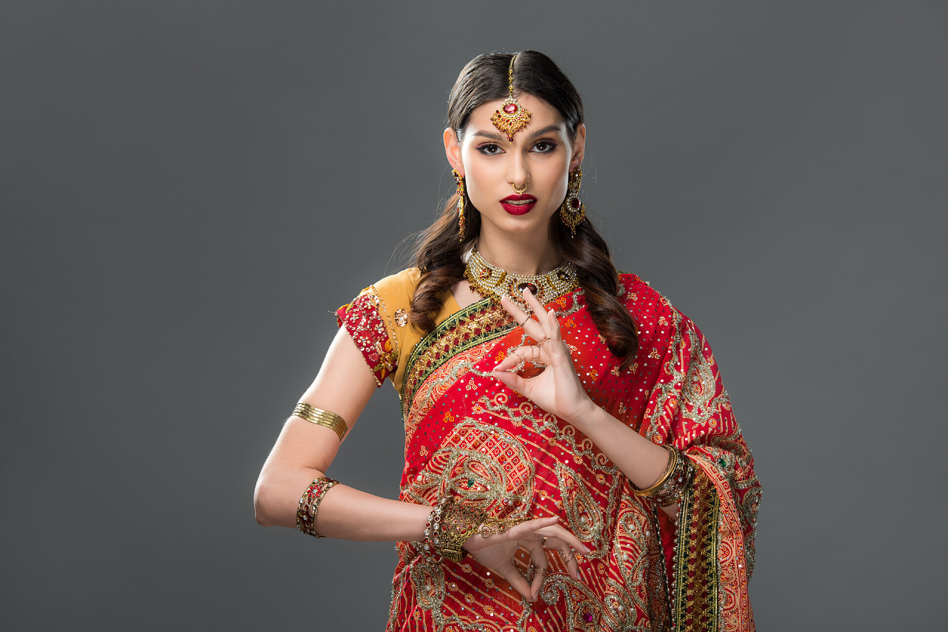 灰色背景中一个美丽高贵的印度妇女有吸引力的印度妇女在萨里和配件与吉安穆德拉, 隔离在灰色 