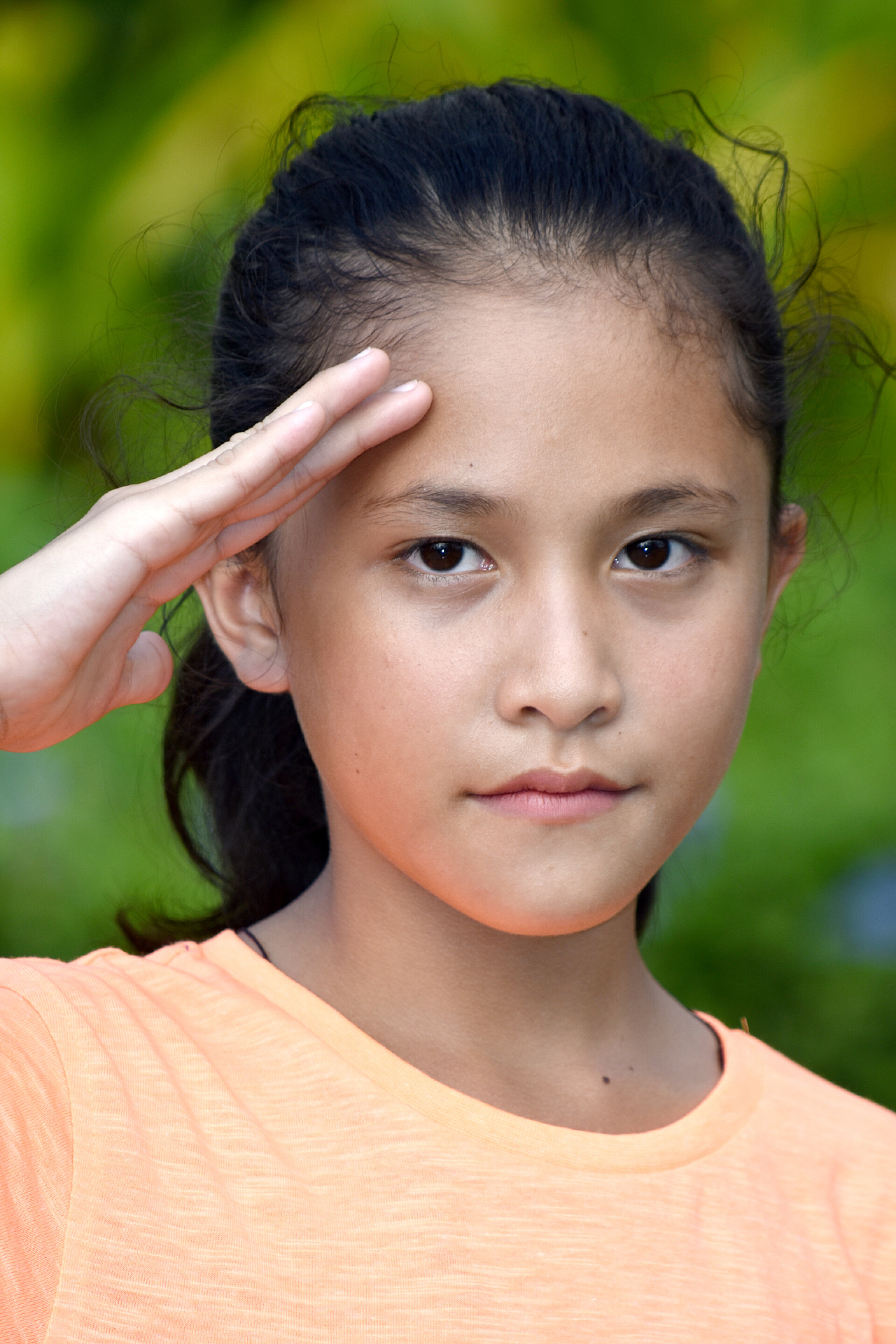 模糊背景上敬礼的小女孩漂亮的菲律宾女孩打招呼