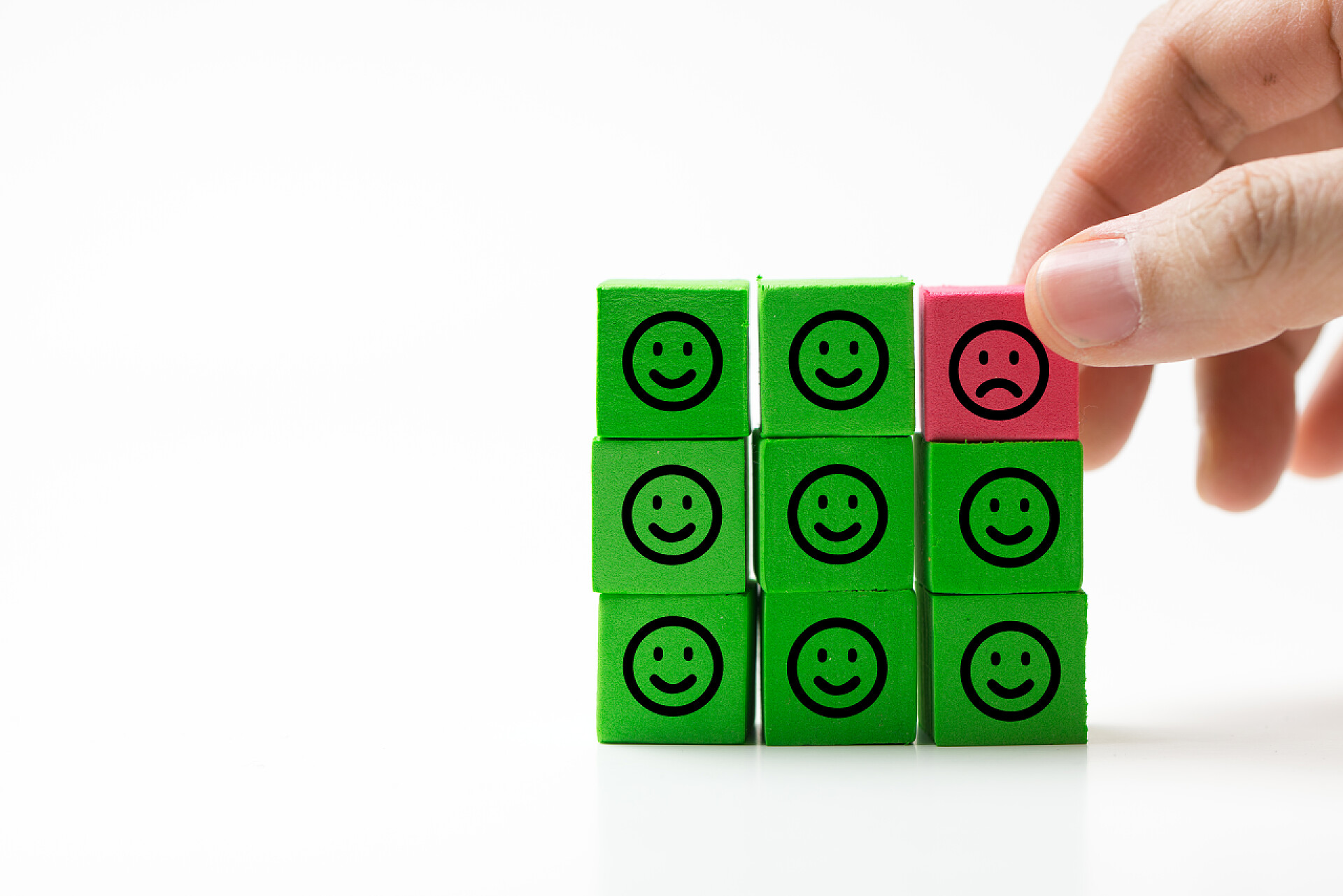 白色背景多个绿色笑脸方块里面有一个红色不开心的方块快乐的笑脸中唯一悲伤的脸