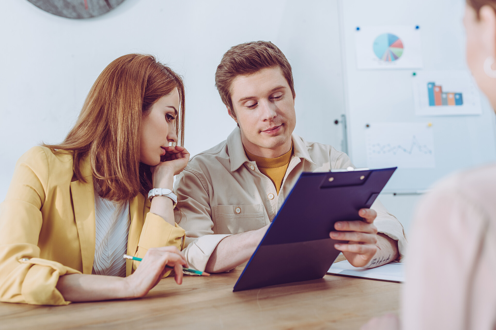 面试中两个面试官在讨论问题在求职面试中, 英俊的招聘人员拿着剪贴板接近有吸引力的同事 