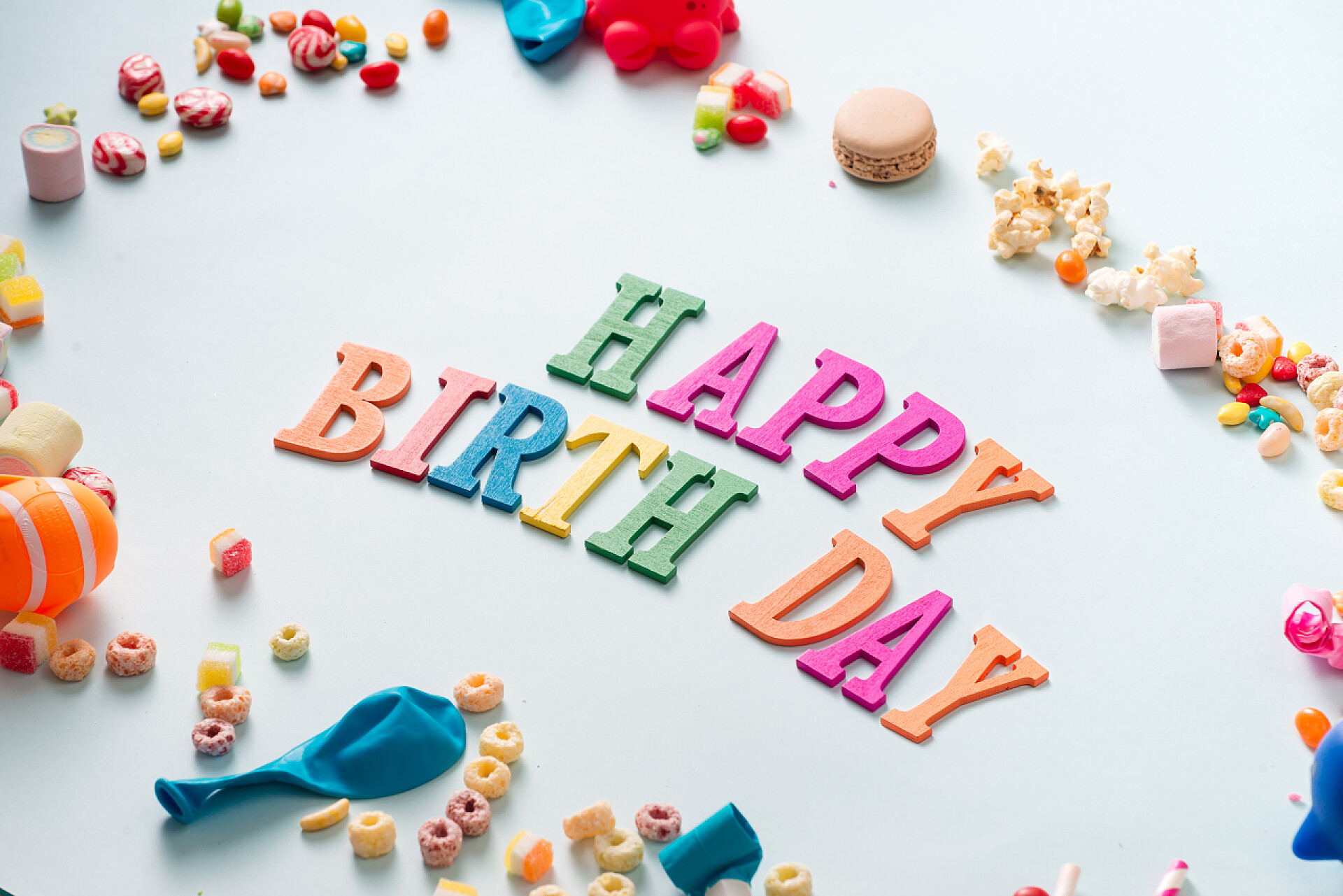 五颜六色的生日庆祝装饰品生日快乐背景或问候传单。五颜六色的节日用品在蓝色桌面视图上。平面布局样式.