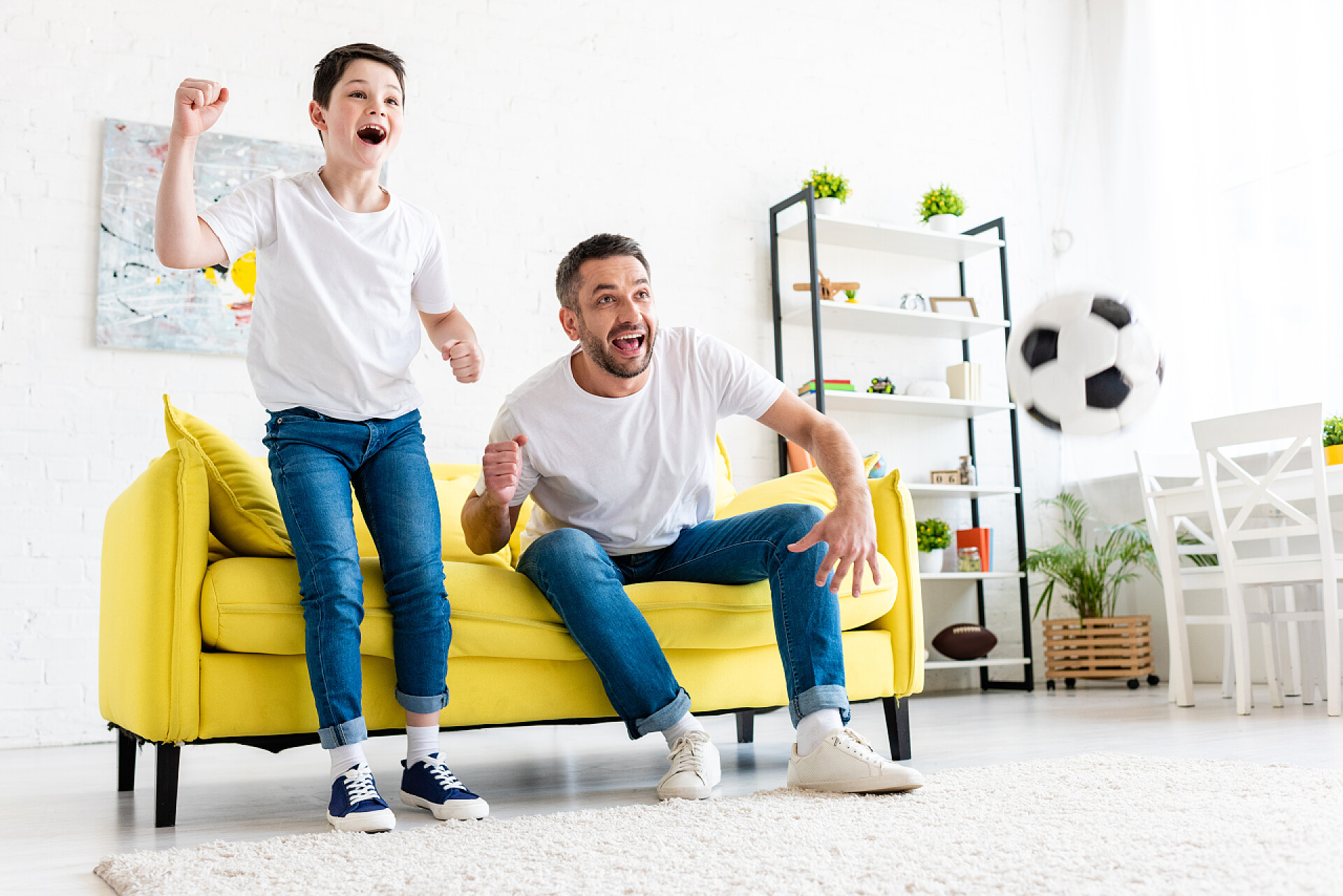 兴奋的父子在客厅观看体育比赛时欢呼雀跃兴奋的父子在客厅观看体育比赛时欢呼雀跃