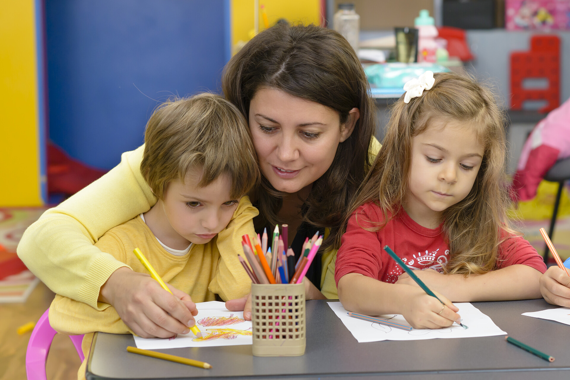 幼儿园里教小朋友画画的老师孩子们和教育家在幼儿园玩游戏
