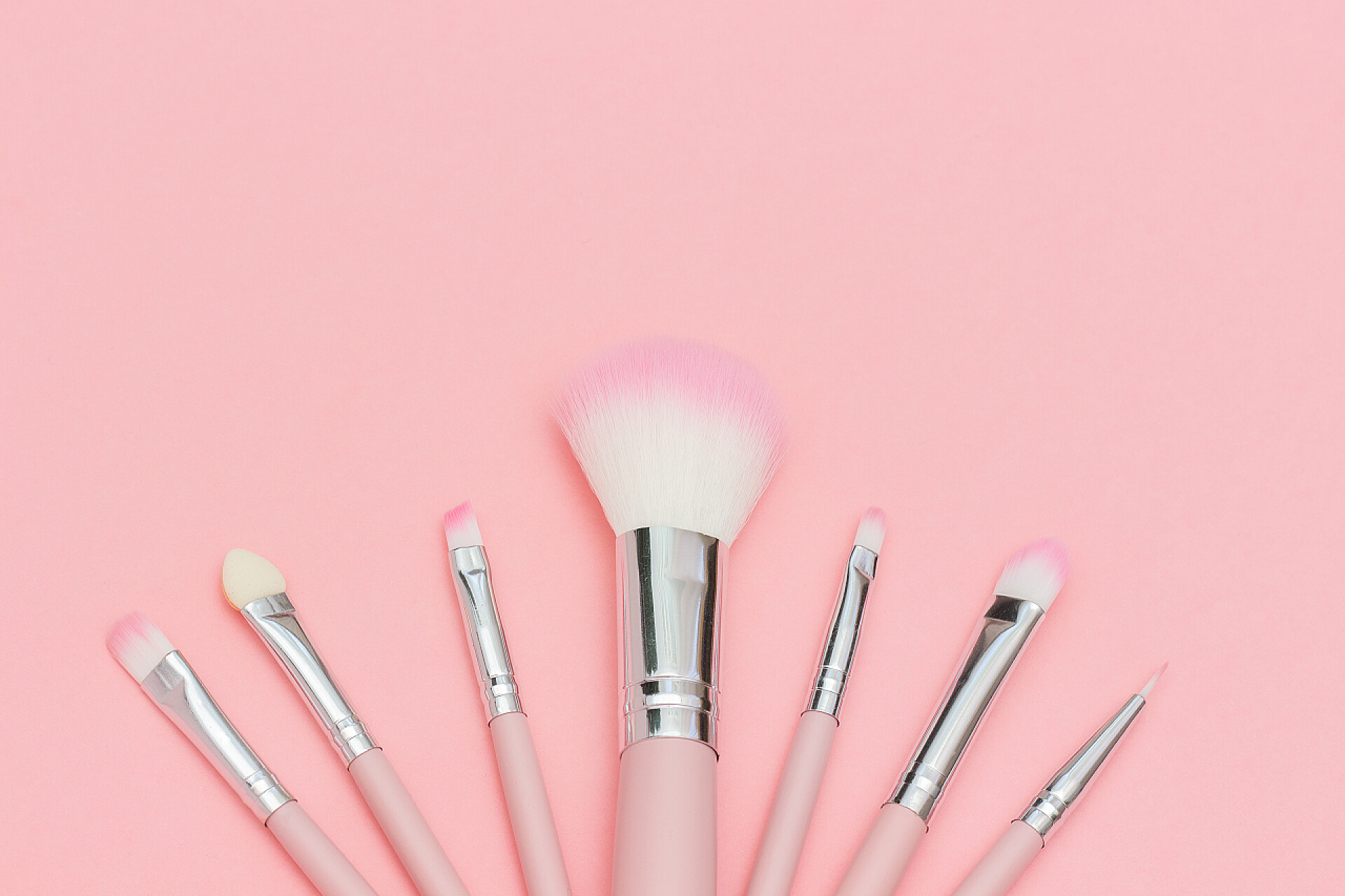在粉色背景上的化妆刷特写粉红化妆刷在柔和的粉红色背景设置
