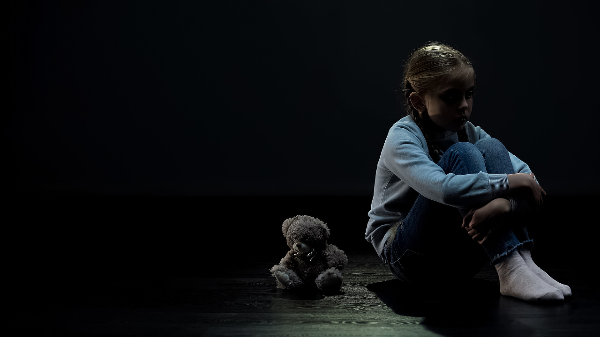 泰迪熊陪伴着小女孩身边小女婴独自坐在暗室里的泰迪熊身边，缺少朋友