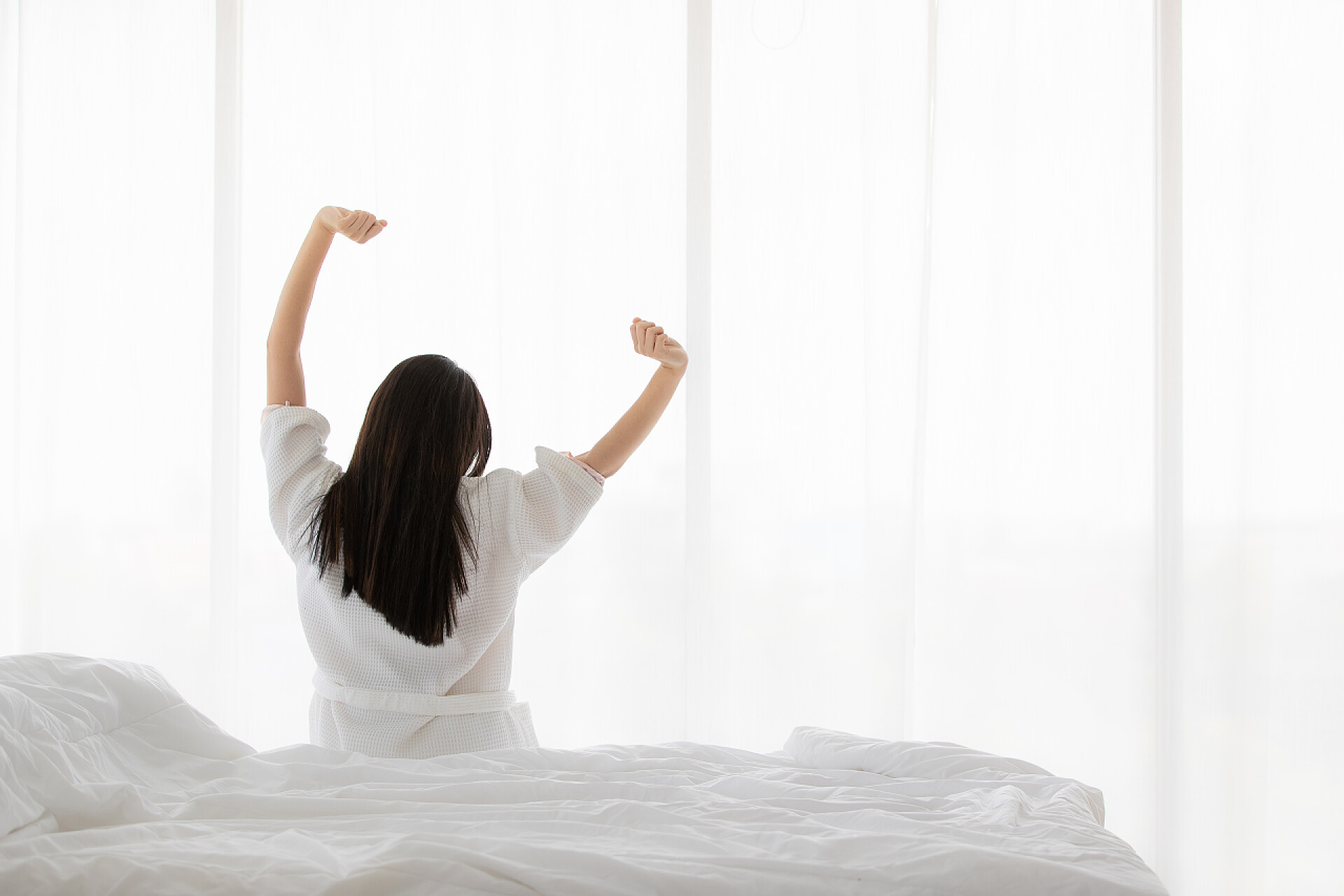 坐在床铺上伸懒腰的女孩