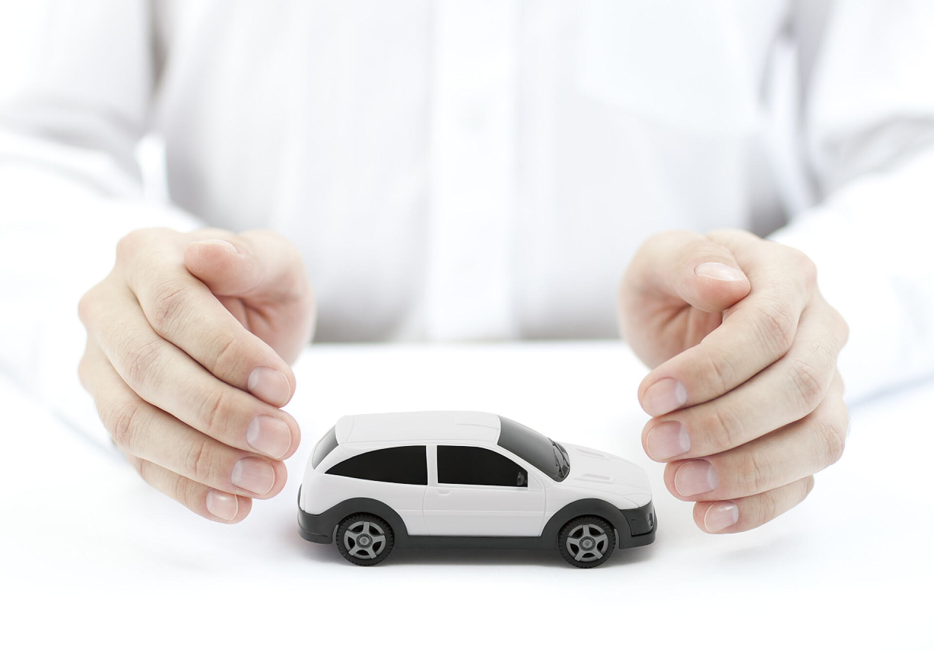代表汽车保险的图片汽车保险的概念与白色汽车玩具覆盖的手 