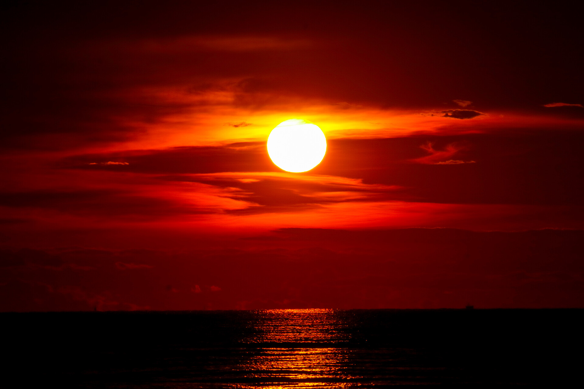最后一抹残阳透过白云照射在海水上日落在海和海最后光红色天空剪影云彩