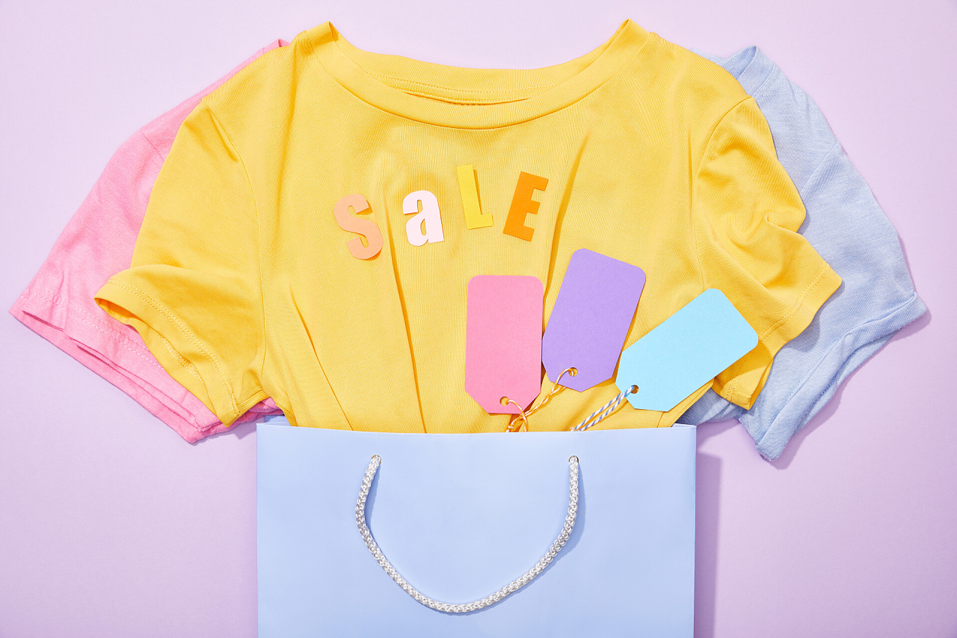 618紫色购物袋里的T恤衫在T恤衫上印有紫色购物袋上五颜六色标签的销售标签