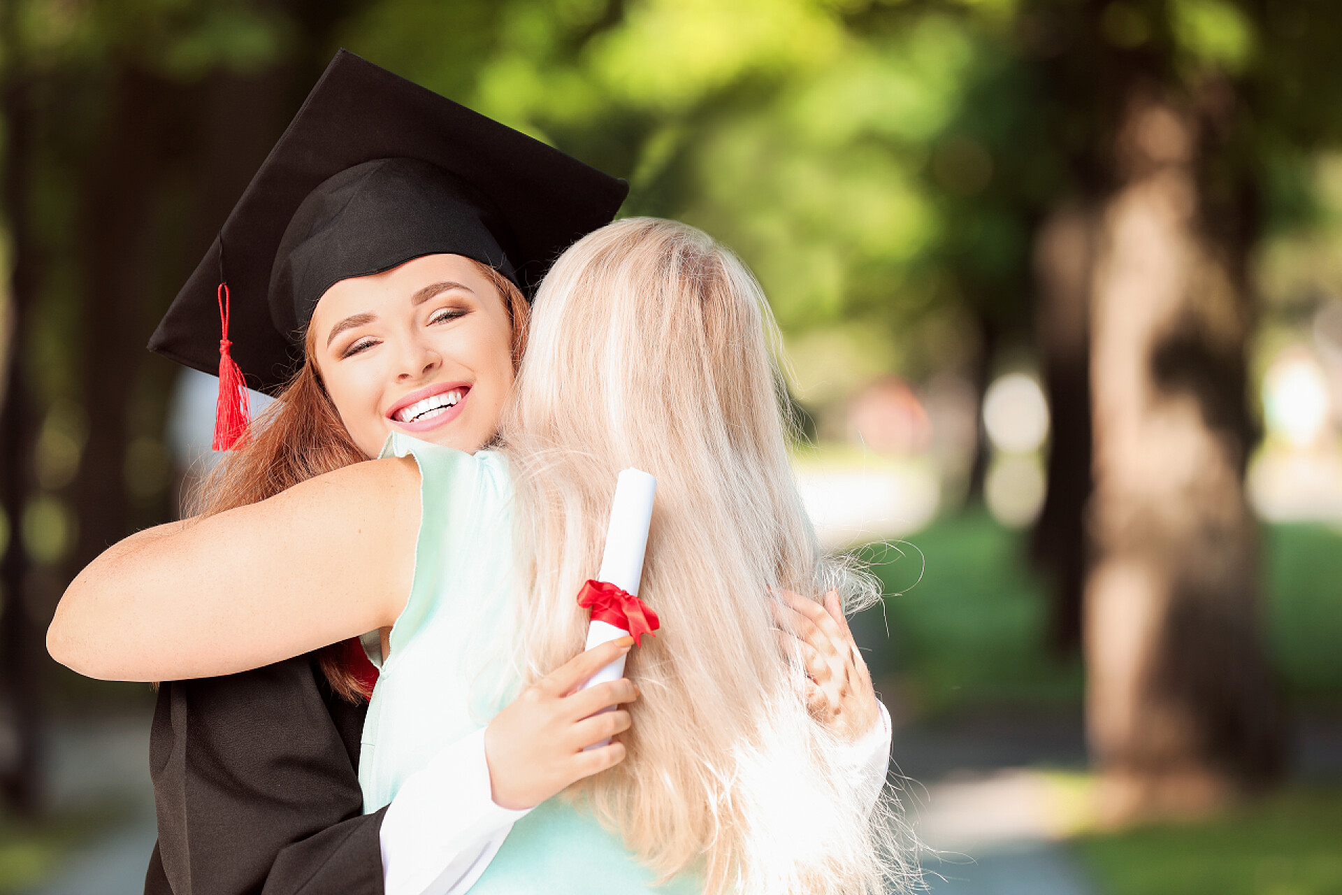 毕业的学生相互拥抱告别快乐的母亲在毕业当天问候她的女儿