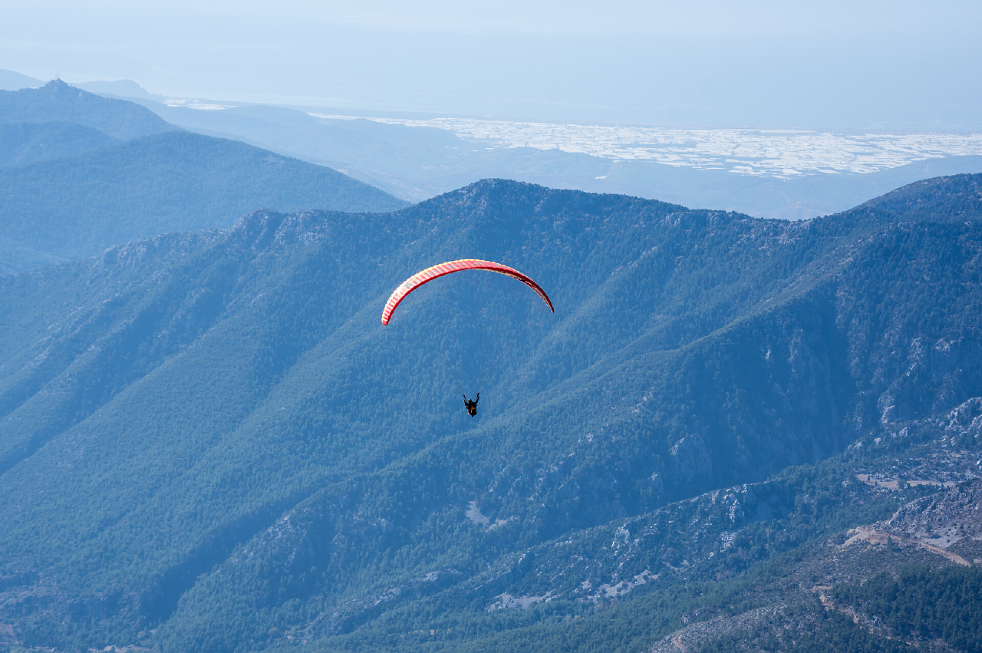 晴朗的天空一个人在山间玩滑翔伞滑翔伞飞越山