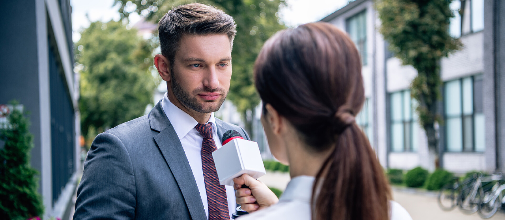 记者拿着麦克风采访男人记者拿着麦克风，与穿着正式服装的商人交谈的全景镜头 