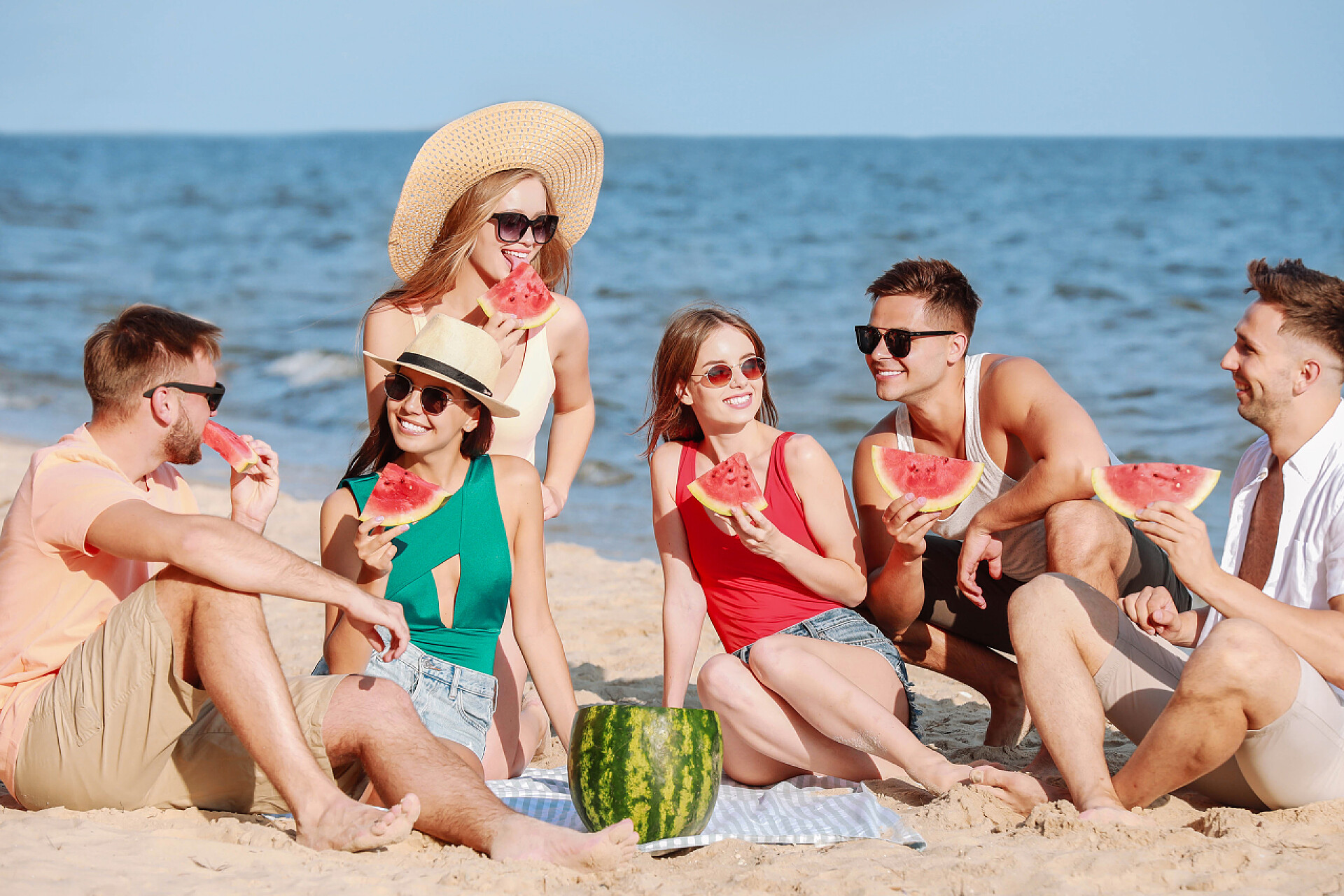 朋友在度假村的海边吃西瓜快乐的朋友在度假村的海边吃西瓜