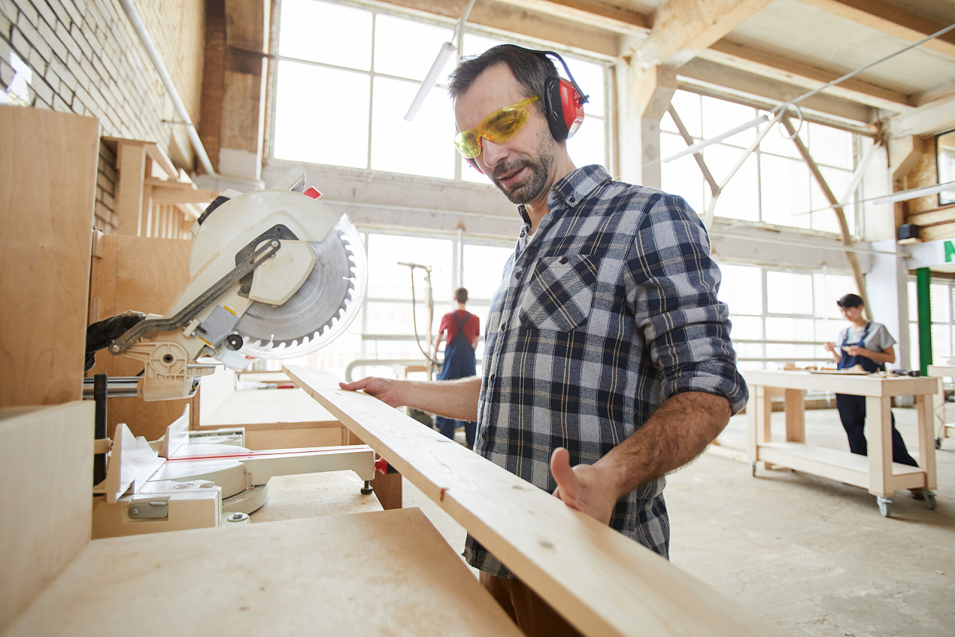 手拿木板的工匠腰起在工业车间的成熟木匠锯木的肖像，复制空间