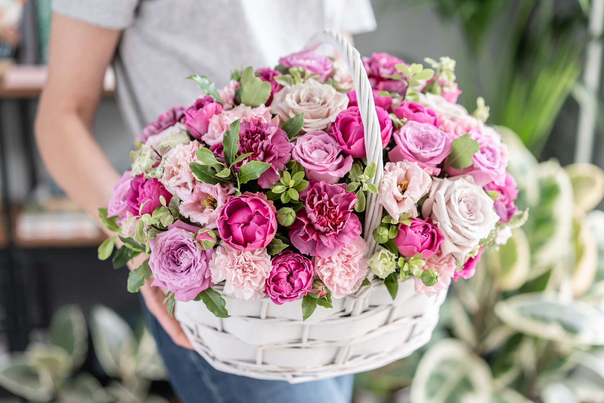 篮子中漂亮的鲜花威克篮子中的花布置。美丽的花束混合花在女人的手。花卉店概念。漂亮的新鲜花束。鲜花递送