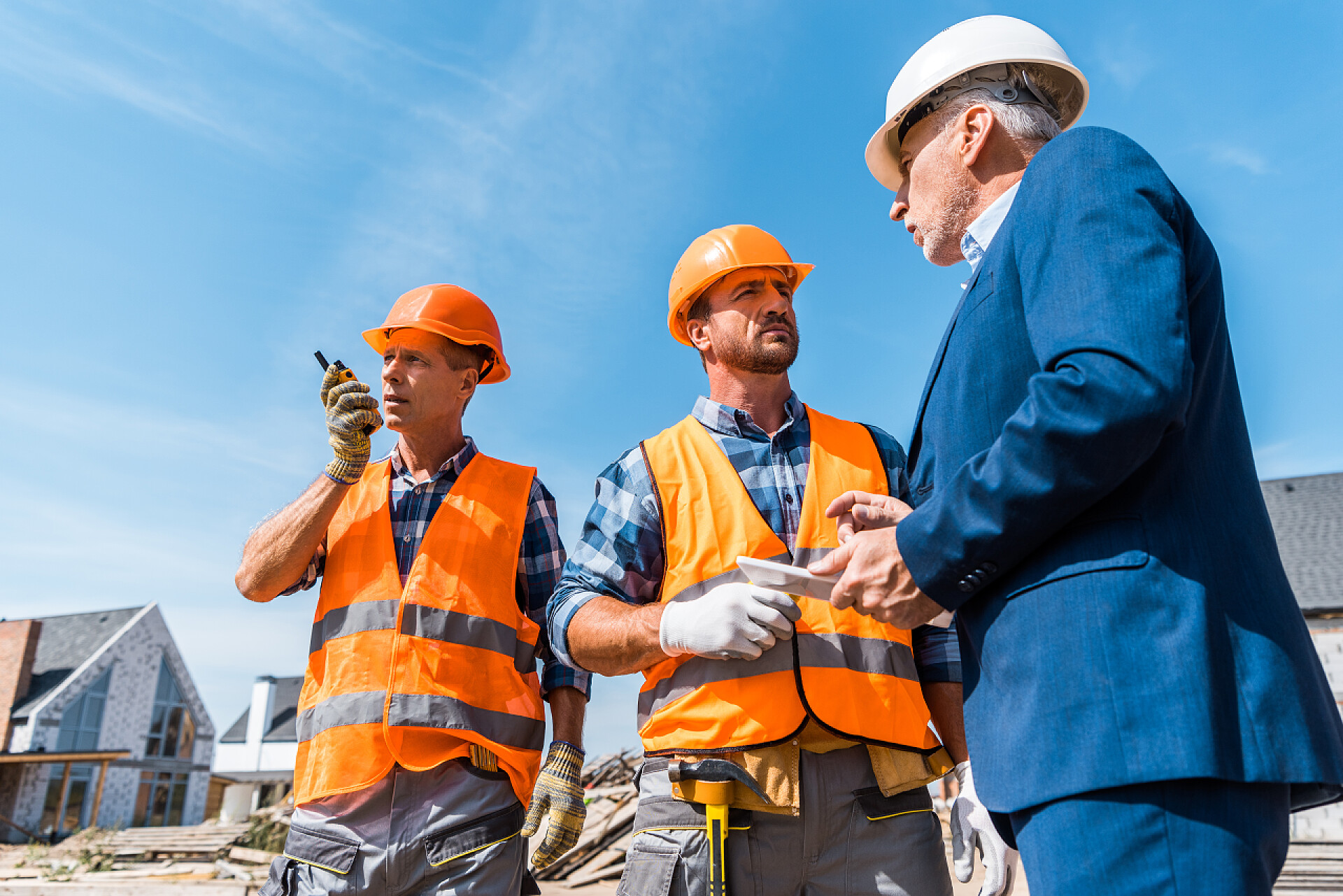 建筑商和商人讨论建筑工程建筑商在同事和商人身边拿着对讲机，带着数码平板电脑 