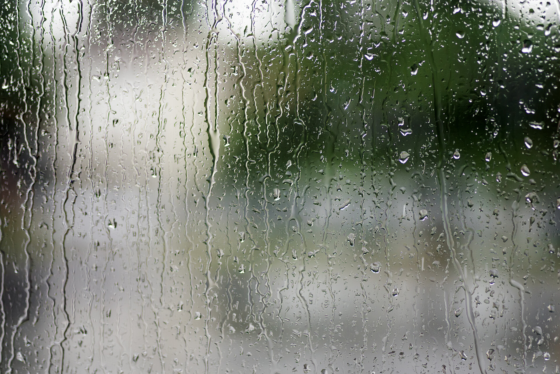 玻璃窗上的水滴雨滴落在窗上，背景为绿色