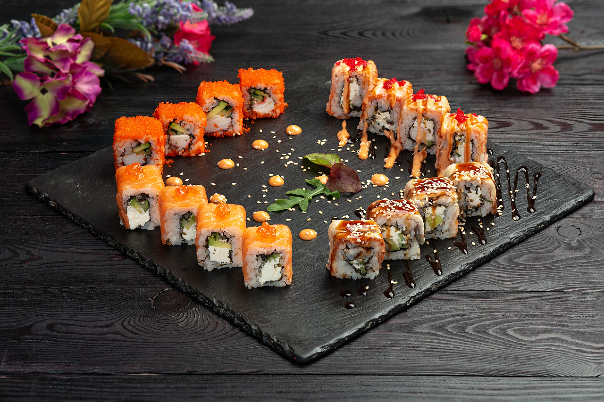 深色木制背景上的寿司玛基寿司卷在黑石上