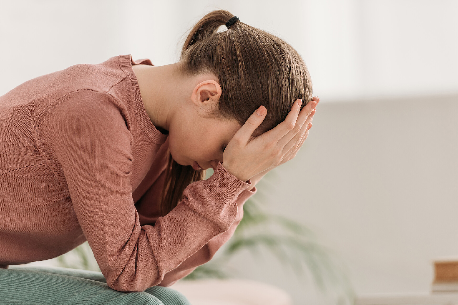 沙发上苦恼的女孩3.年轻女子坐在沙发上，双手托着头，患上了偏头痛