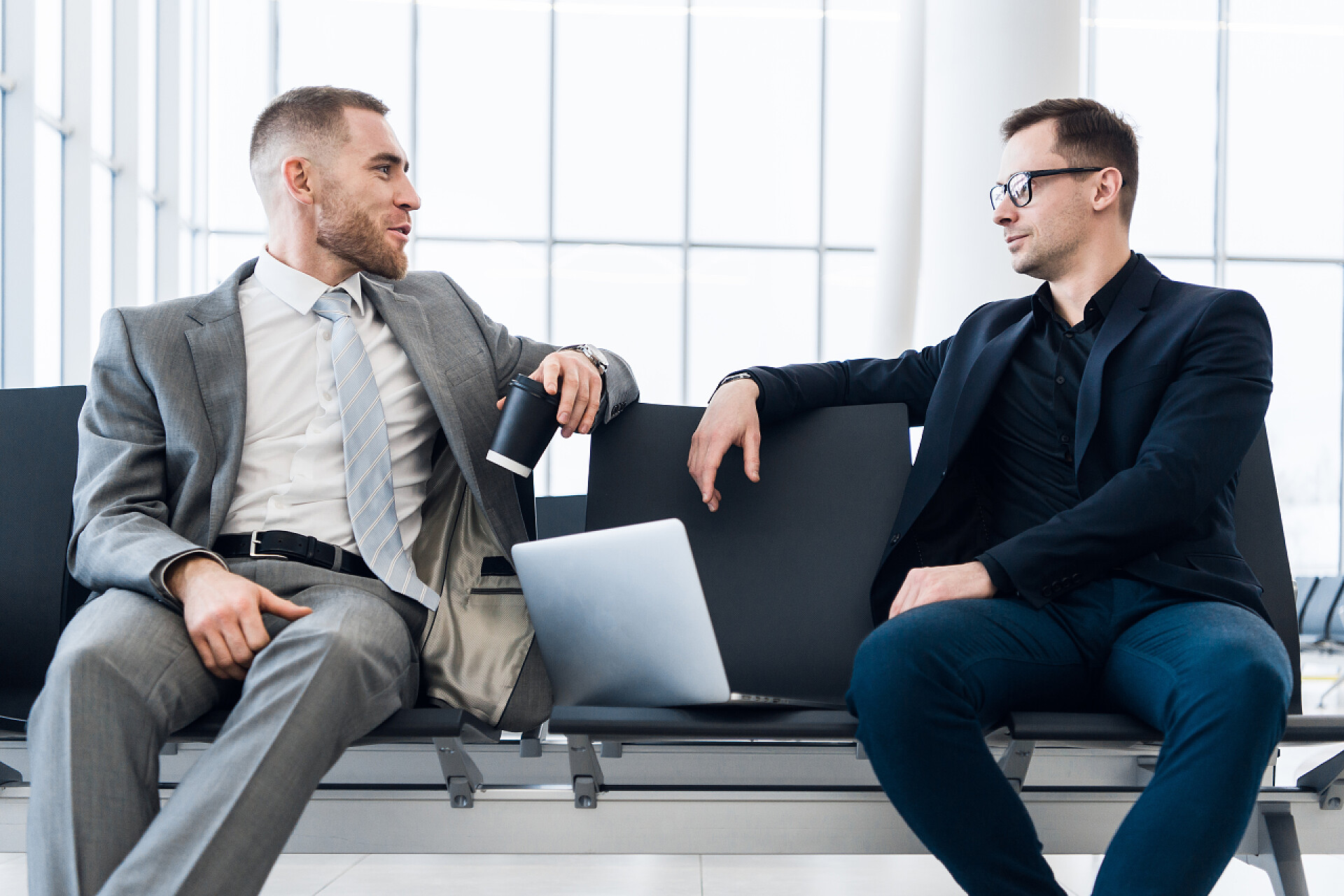 商人们一起在机场休息室的笔记本电脑上工作商人们一起在机场休息室的笔记本电脑上工作