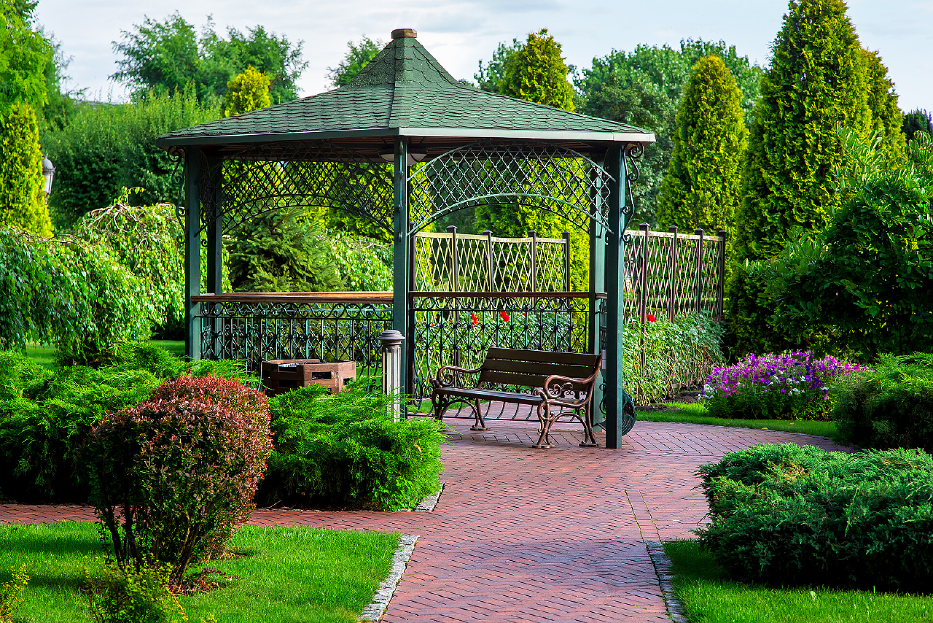 森林公园里的绿植和凉亭长椅夏日有屋顶、有绿色植物、灌木和树木的公园长椅的铁凉亭.