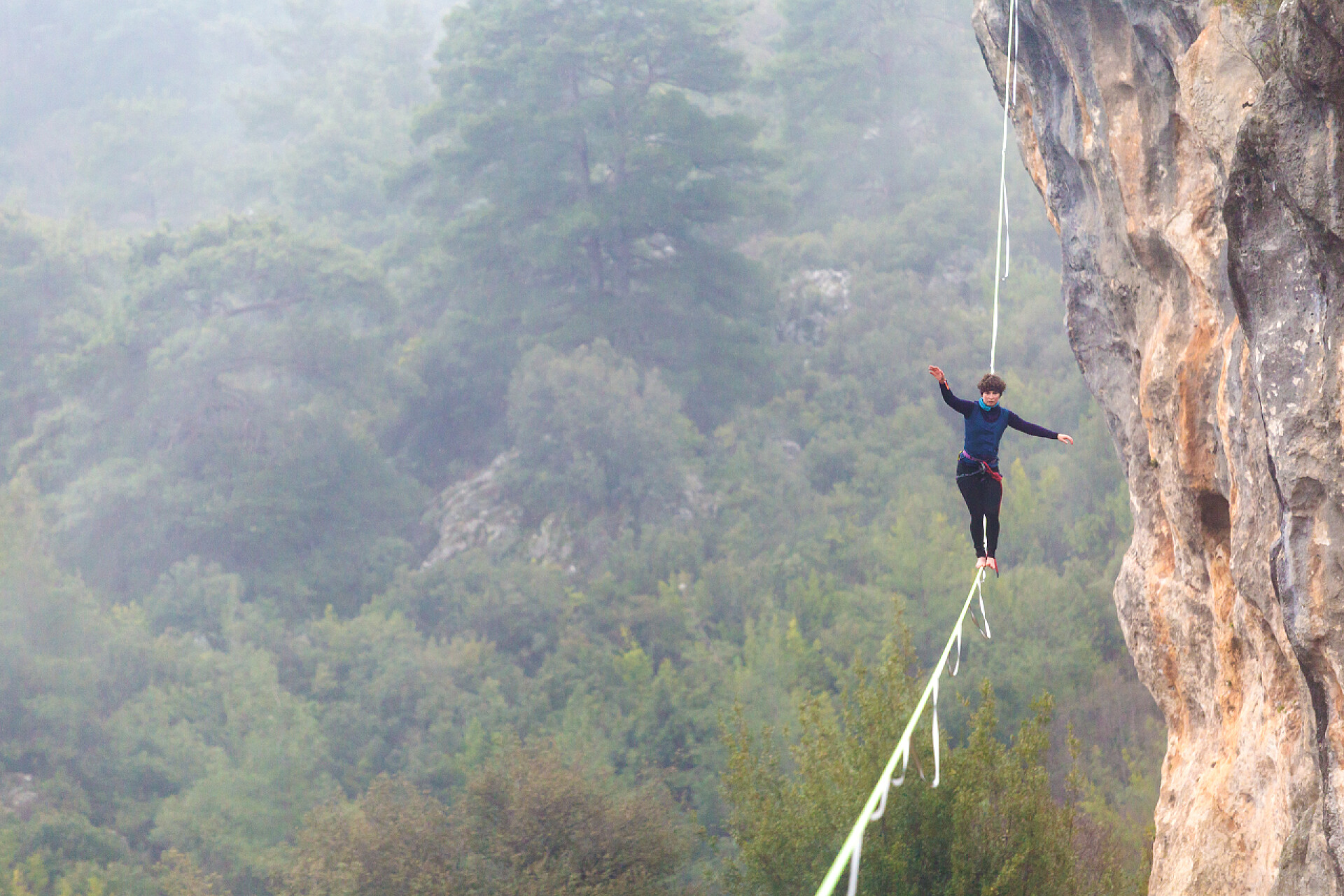 在悬崖峭壁上走钢丝的极限运动员高山上的高线.
